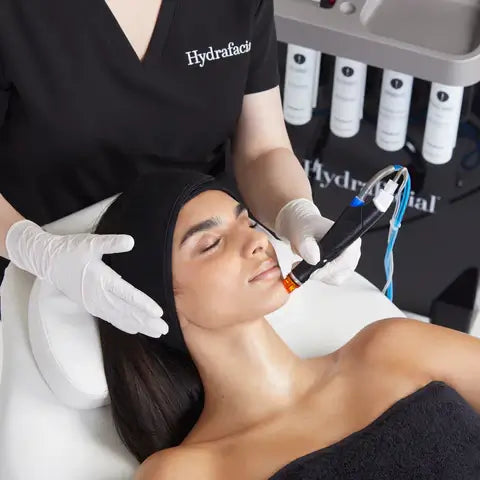 Kvinne får Hydrafacial behandling for glødende hud med profesjonell ansiktsbehandling.